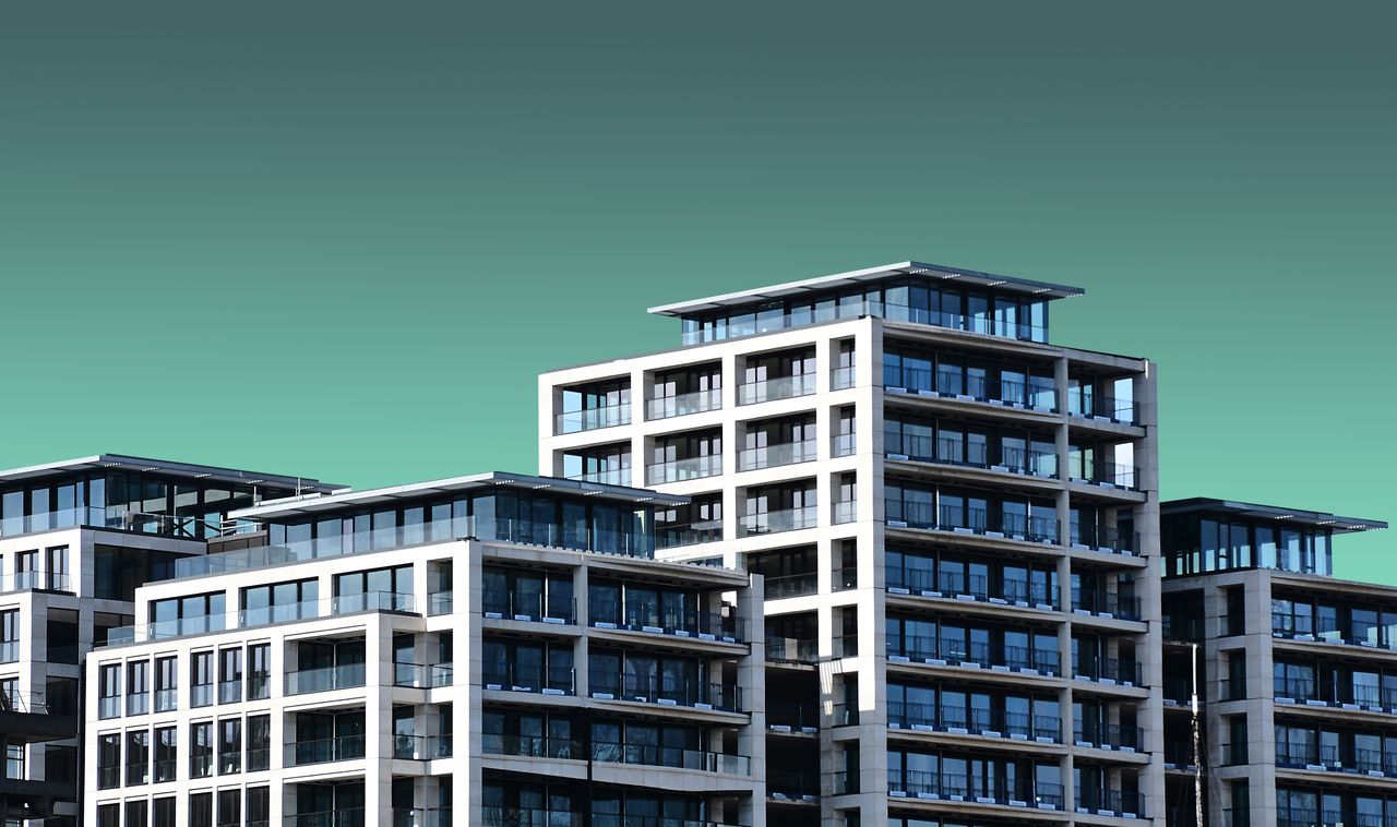 The Art of Drawing Readers In: Your attractive post title goes here Contemporary apartment buildings with a minimalist design are set against a clear blue sky.